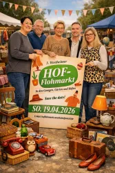 Fünf Personen stehen lächelnd vor einem Schild für den Hof-Flohmarkt. Im Hintergrund sind Stände und verschiedene Gegenstände zu sehen.