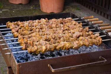 Leckere gegrillte Fleischspieße auf einem Grill. Die Spieße sind gleichmäßig angeordnet und haben eine köstliche, goldbraune Farbe.