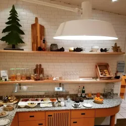 Eine gemütliche Frühstücksecke mit verschiedenen Speisen auf einem Granit-Tisch. Regale mit Gläsern und Deko verleihen der Atmosphäre einen einladenden Touch.