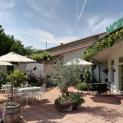Eine gemütliche Terrasse eines Hotels mit Tischen und Sonnenschirmen. Der Bereich ist mit Pflanzen und Blumen schön dekoriert.