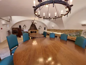 Ein stilvoller Konferenzraum mit einem runden Holztisch und blauen Stühlen. Die Decke ist mit einem großen, modernen Kronleuchter geschmückt.