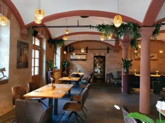 Ein gemütliches Restaurant mit warmem Licht und modernen Möbeln. Pflanzen und dekorative Elemente schaffen eine einladende Atmosphäre.