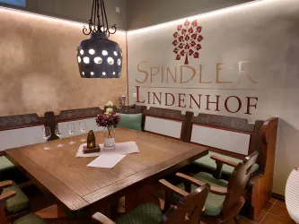 Ein gemütlicher Speisesaal mit Holzstühlen und einem großen Tisch. An der Wand ist das Logo "Spindler Lindenhof" zu sehen.