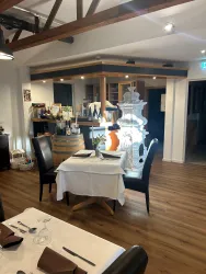 Ein elegantes Restaurant mit Holzboden und warmem Licht. Zwei gedeckte Tische und eine ansprechende Bar im Hintergrund schaffen eine einladende Atmosphäre.