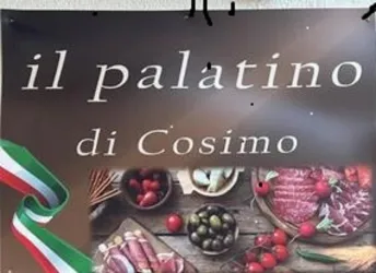 Ein Schild mit dem Schriftzug "il palatino di Cosimo". Im Hintergrund sind verschiedene Wurst- und Käseprodukte sowie Gemüse zu sehen.