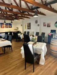 Ein gemütliches Restaurant mit Holzdecke und eleganten Tischen. Die Atmosphäre ist einladend und bietet einen Blick auf einige dekorative Elemente.