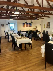 Ein einladendes Restaurant mit Holzbalkendecke und eleganten Tischen. Die Atmosphäre ist gemütlich und freundlich.