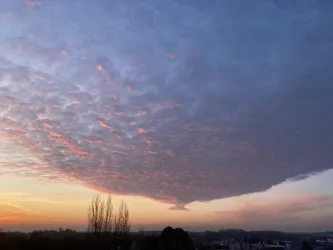 Ein beeindruckender Himmel mit bunten Wolken und einem sanften Sonnenuntergang. Die Stimmung ist ruhig und einladend.