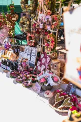 Ein Marktstand mit handgefertigten Waren und Dekorationen. Es gibt Blumen, Süßigkeiten und Kunsthandwerk zu sehen.