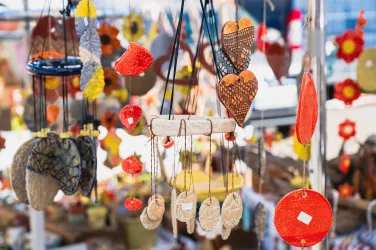 Bunte handgefertigte Schmuckstücke hängen an Ständen. Die Vielfalt umfasst Herzen, Anhänger und dekorative Elemente.