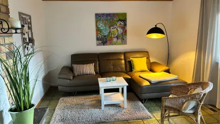 Ein gemütliches Wohnzimmer mit einem Ledersofa und einem wunderschönen Bild an der Wand. Eine Stehleuchte und ein kleiner Tisch ergänzen die Einrichtung.