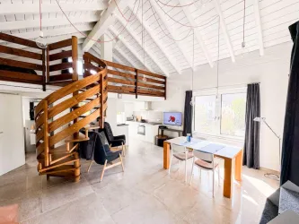 Eine helle, moderne Wohnung mit einer offenen Raumaufteilung. Die Holztreppe führt in den oberen Bereich, während der Essbereich gemütlich eingerichtet ist.