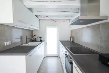 Eine moderne voll ausgestattete Küche mit Herd, Backofen, Geschirrspülmaschine, Nespresso-Maschine, Toaster und Wasserkocher.