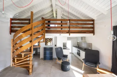 Ein modernes, helles Zimmer mit einer gemütlichen Treppe aus Holz. Die Einrichtung besteht aus eleganten Möbeln und einer offenen Küche.