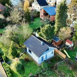 Ein gemütliches Haus umgeben von grünen Bäumen und Sträuchern. Der Garten ist gut gepflegt und bietet einen einladenden Eindruck.