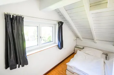 Der Schlafbereich ist mit 3 Einzelbetten ausgestattet. Paare nutzen gerne die beiden nebeneinander stehenden Einzelbetten, alleinreisende das separat stehende, was sonst als Sitzgelegenheit oder Ablage dient. Aufgrund der Dachschräge ist das Haus mit den Designklassikern "Stapelbett von Rolf Heide" ausgestattet, die mit einer Höhe von ca. 35 cm relativ tief sind.