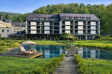 Ein modernes Hotelgebäude inmitten der Natur. Eine ruhige Umgebung mit einem Teich und einem Holzsteg.