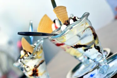 Drei köstliche Eisschalen mit Sahne und Schokoladensauce. Jede Schale ist mit einer Waffel dekoriert.