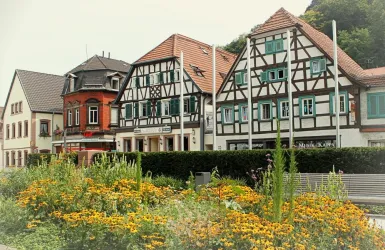 Eine malerische Straße mit traditionellen Fachwerkhäusern. Bunte Blumen schmücken den Vordergrund.