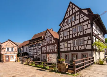 Ein malerisches Fachwerkhaus mit weißen Wänden und dunklen Balken. Es ist ein sonniger Tag mit klarem Himmel.