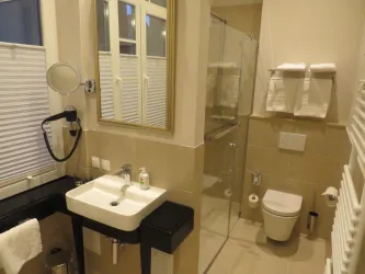 Ein modernes Badezimmer mit Dusche, Waschbecken und Toilette. Die Wände sind hell und die Ausstattung ist schlicht und elegant.