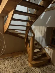 Eine elegante Holztreppe mit geschwungenen Stufen. Der Boden ist mit dekorativen Fliesen gestaltet.