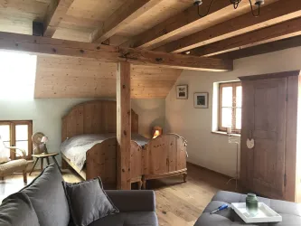 Ein gemütliches Schlafzimmer mit Holzvertäfelung und einem großen Bett. Der Raum ist hell und freundlich mit Fenstern, die natürliches Licht hereinlassen.