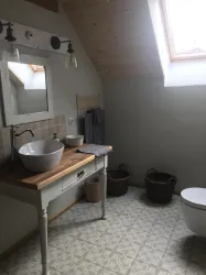 Ein modernes Badezimmer mit einer Holzwaschtisch und einer großen Schüssel. Es gibt einen großen Spiegel und natürliche Lichtquelle durch ein Fenster.