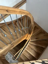 Eine geschwungene Treppe aus Holz mit einem eleganten Geländer. Der Boden ist aus Holz mit einem schönen Muster.