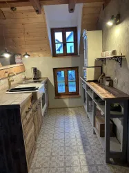 Eine moderne Küche mit Holzmöbeln und hellen Wänden. Es gibt ein Fenster, das Tageslicht hereinscheinen lässt.