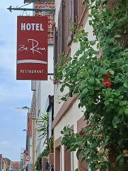 Ein Hotel mit dem Namen "Zum Riesen" ist an der Wand befestigt. Neben dem Eingang ist eine grüne Pflanze zu sehen.