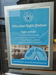 Ein Schild einer Refill-Station mit Informationen zu nachhaltigem Wasserkonsum. Es fördert das Auffüllen von Wasserflaschen und die Vermeidung von Plastik.
