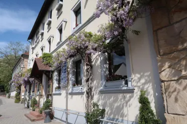 Ein hübsches Gebäude mit blühenden Pflanzen entlang der Fassade. Die Fenster sind stilvoll gestaltet und laden zum Verweilen ein.