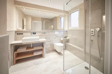 Ein modernes Badezimmer mit einer gläsernen Dusche und einem Waschbecken auf einem Holzregal. Die Wände sind hell und zeitgemäß gestaltet.