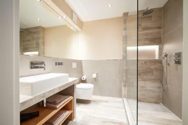 Ein modernes Badezimmer mit einer Walk-in-Dusche und einem stilvollen Waschbecken. Die neutrale Farbpalette sorgt für eine ruhige Atmosphäre.