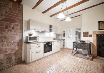 Eine moderne Küche mit hellen Schränken und einer attraktiven Arbeitsplatte. Die Mischung aus modernen und rustikalen Elementen schafft eine einladende Atmosphäre.