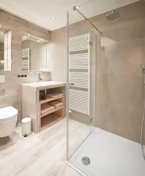 Ein modernes Badezimmer mit einer gläsernen Dusche und eleganten Fliesen. Die Ausstattung umfasst ein Waschbecken und einen Handtuchheizkörper.