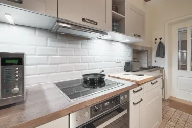 Eine moderne Küche mit hellen Schränken und einer eleganten Fliesenrückwand. Sie ist gut ausgestattet mit einem Herd und einer Mikrowelle.