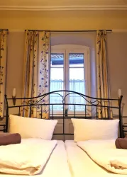 Ein gemütliches Schlafzimmer mit einem Doppelbett und hellen Vorhängen. Das Fenster bietet einen Blick nach draußen und sorgt für natürliches Licht.