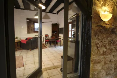 Ein gemütlicher Innenraum mit einem Essbereich und einer Sitzecke. Die Wände sind aus Stein, und es gibt große Fenster, die eine einladende Atmosphäre schaffen.