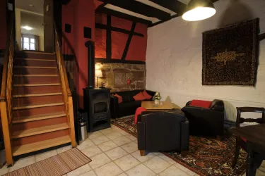 Ein gemütliches Wohnzimmer mit einer Treppe, einer Sitzecke und einem Holzofen. Die Wände sind teilweise rot gestrichen und es gibt einen schönen Teppich auf dem Boden.