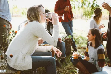 Eine Gruppe von Freunden genießt Getränke im Freien. Menschen sitzen zusammen und verbringen eine entspannte Zeit in der Natur.