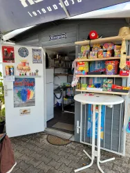 Ein kleiner Kiosk mit bunten Süßigkeiten und Spielen. Der Eingangsbereich ist einladend und freundlich gestaltet.