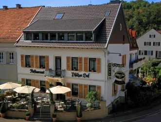 Ein charmantes Restaurant mit einem einladenden Außenbereich und Sonnenschirmen. Das Gebäude hat eine traditionelle Architektur mit Holzläden.