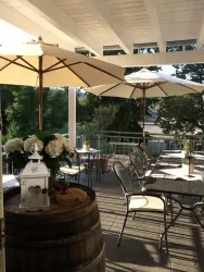 Eine gemütliche Terrasse mit Sonnenschirmen und Tischen. Blumen und eine Laterne verschönern den Raum.