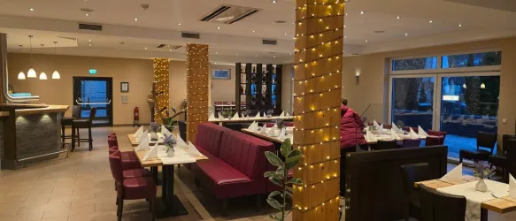 Ein gemütliches Restaurant mit eleganter Beleuchtung. Die Tische sind schön gedeckt und die Atmosphäre ist einladend.