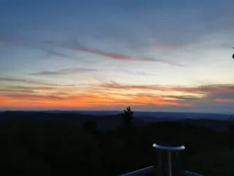 Ein schöner Sonnenuntergang über den Hügeln. Der Himmel ist mit orangefarbenen und lila Wolken gefärbt.