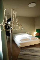 Ein modernes Schlafzimmer mit einem gemütlichen Bett und einer eleganten Stehlampe. Der Raum hat eine helle und freundliche Atmosphäre.