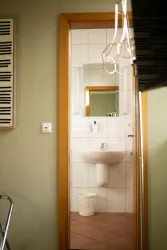 Ein modernes Badezimmer mit weißen Fliesen und einer schlichten Waschgelegenheit. Der Raum ist gut beleuchtet und wirkt sauber und einladend.