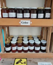 Eine Holzkiste mit verschiedenen Gläsern von Gelee. Die Gläser sind ordentlich aufgereiht und tragen Etiketten mit den Geschmacksrichtungen.